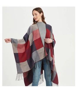 Détail de la bordure à franges sur un châle poncho écossais rouge et bleu pour femme