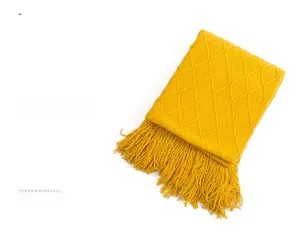 Detail of ginger yellow knitted throw blanket with 3D diamond texture and long fringes