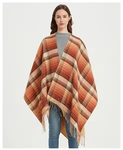 Detail showing orange and brown plaid pattern and long tassel hem on the poncho