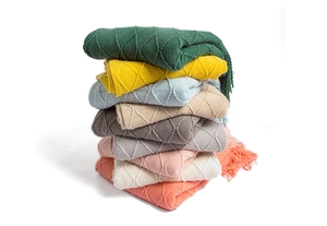 Detail of knitted throw blankets with diamond pattern and decorative fringe tassels