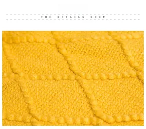 Macro detail of ginger yellow knitted blanket showing 3D diamond pattern and fringe