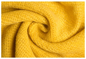 Macro shot of mango yellow waffle knit texture on a soft and cozy tassel blanket