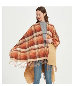 Detail of soft checkered poncho wrap with orange and brown plaid and tassel hem