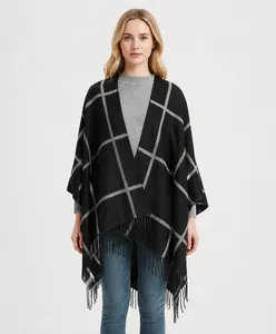 Detail of soft black and grey plaid poncho with elegant fringe hem and knit texture