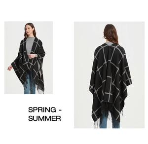 Close-up of black and white checkered poncho featuring elegant fringed hem detail