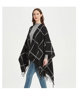 Detail of checkered poncho featuring fringe hem and soft knit black and grey pattern