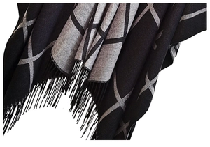 Close-up of black and grey plaid knit poncho featuring fine fringe trim details