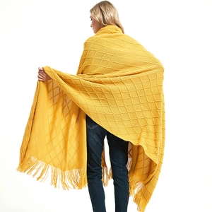 Bright yellow knitted throw blanket with diamond patterns and decorative fringe tassels