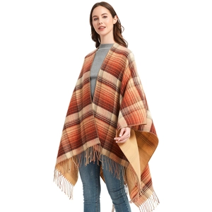 Women's autumn plaid poncho wrap with orange and brown tassels over a grey sweater