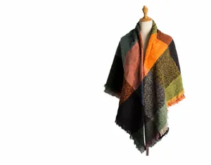 Détail macro d'une écharpe à carreaux épais avec motifs orange et verts et franges