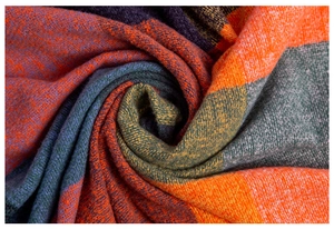 Close-up of thick checkered scarf fabric showing soft brushed texture and orange green plaid