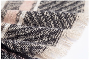 Close-up of pink and grey herringbone knit fabric with soft fringe detail on shawl
