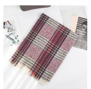 Detail showing colorful bouclé yarn check pattern and fine tassels on a warm shawl