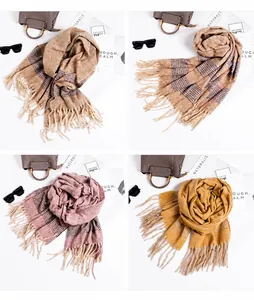 Detail view of plaid tassel scarves in beige, brown, pink and yellow with soft texture
