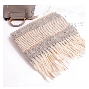 Detail of soft knit scarf with grey tweed texture, colorful stripes and cream tassels