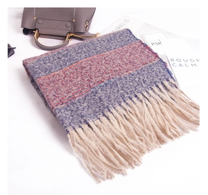 Detail of soft gray-blue striped knit scarf with thick cream tassels for winter