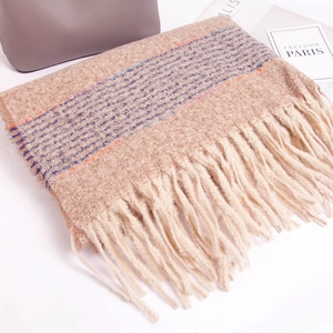 Close-up of a soft beige knit scarf with blue stripes and thick fringe tassels