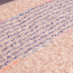 Macro view of soft fuzzy striped scarf showing beige fabric texture and plush fibers
