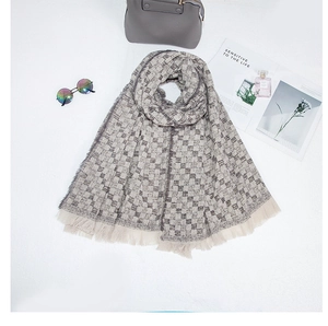 Posa piatta di una sciarpa a quadri grigio e beige con frange e accessori alla moda