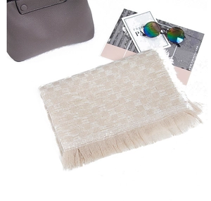 Dettaglio di sciarpa in maglia beige chiaro con trama a scacchi e frange delicate