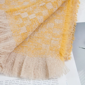 Dettaglio macro della sciarpa a maglia a scacchi giallo zenzero e beige con frange