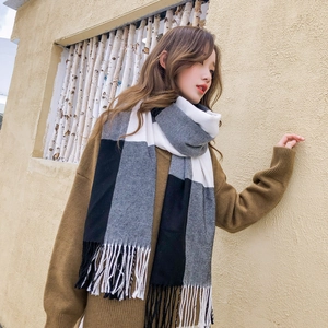 Détail d'une écharpe d'hiver à carreaux noir blanc et gris avec de longues franges souples
