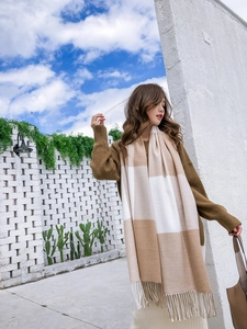 Gros plan d'une écharpe à carreaux beige et blanc effet cachemire avec des franges