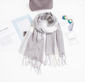 Détail d'une écharpe à carreaux gris et blanc en faux cachemire avec pompons et accessoires
