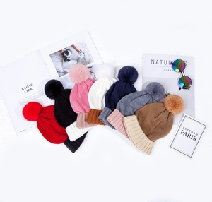 Flat lay of colorful knit beanies with large pom-poms and ribbed cuffs for kids