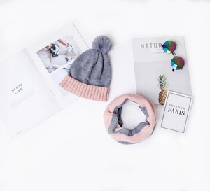 Detailed flat lay of children's thick knitted hat and scarf set in grey and pink tones
