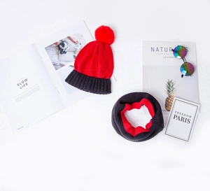Detail of red and black knit winter set with thick pompom hat and warm loop scarf