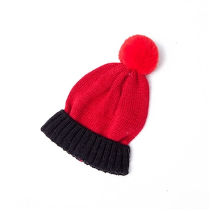 Close-up of red and black color-block knit hat with a large red pompom detail