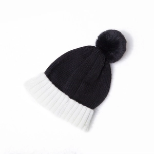 Detail of kids knit beanie with black body and contrast white ribbed brim with pom-pom