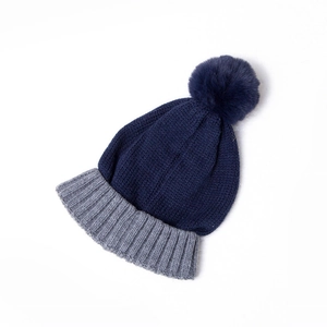 Close-up of the thick knit texture and pom-pom detail on the blue and grey winter hat