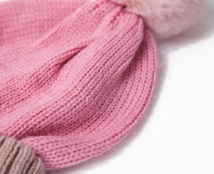 Detail of pink knitted beanie featuring soft pom-pom and thick ribbed texture design