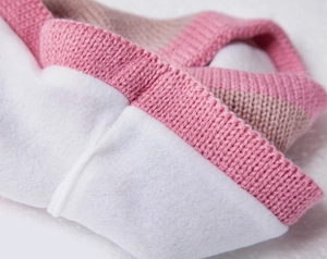 Detailed close-up of striped pink and beige knit fabric with warm white fleece lining