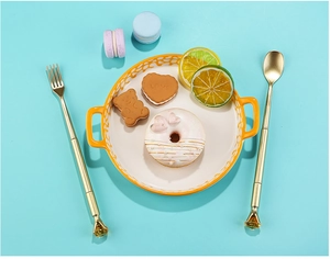 Creative cutlery shaped pens with yellow crystals on a ceramic plate with sweets