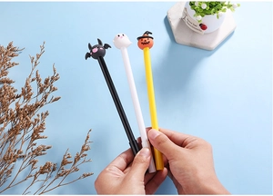 Detail of hand holding Halloween pens with pumpkin, ghost, and bat cartoon toppers