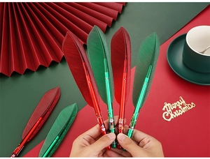 Detail of Christmas leaf-shaped pens with Santa and reindeer patterns on a festive backdrop