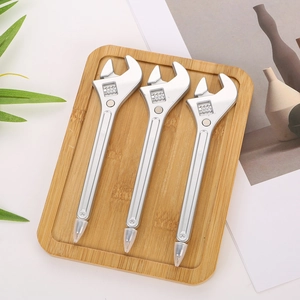 Trois stylos créatifs en forme de clé à molette argentée sur un plateau en bois naturel