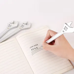 Gros plan d'un stylo gel créatif en forme de clé à molette écrivant sur un carnet ligné