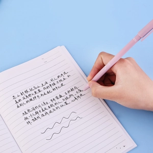 Close-up of a matte mauve gel pen held in hand writing on a white notebook page
