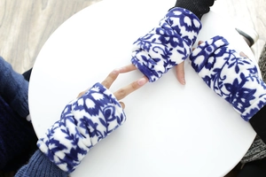 Detalle de guantes sin dedos de franela gruesa con flores azules y blancas sobre mesa