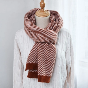 Detail view of caramel brown herringbone knit scarf with thick ribbed edges on a mannequin