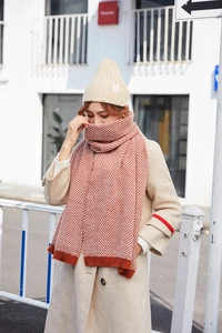 Detail of orange herringbone knitted scarf and beige ribbed beanie set for winter wear