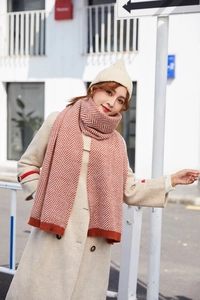 Detail of orange and white herringbone knit scarf paired with a beige beanie