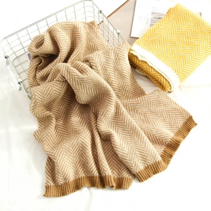 Detail of tan and white herringbone knit scarf with ribbed edge and soft texture