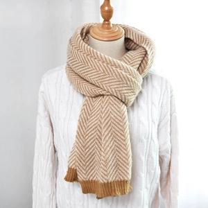 Detail of ginger herringbone knit scarf showing thick texture and ribbed hem on model