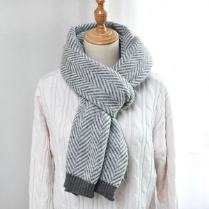 Detailed view of gray herringbone knit scarf with thick ribbed edge on a mannequin