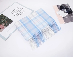 Flat lay of soft blue plaid tassel scarf with sunglasses and fashion magazine